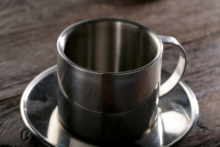 钢的茶杯和茶碟上木背景特写