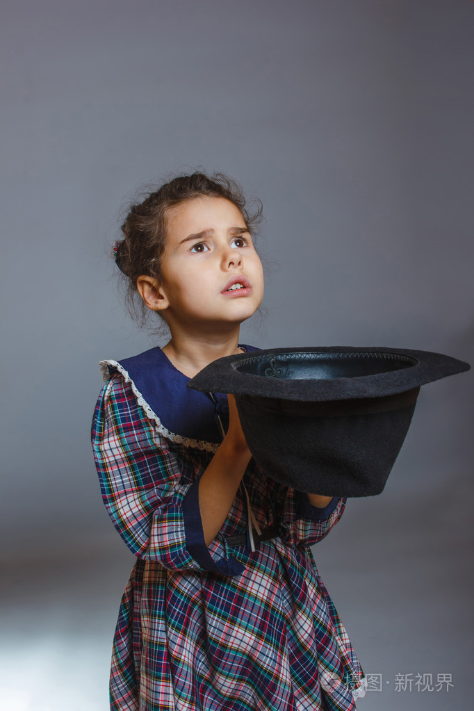 在灰色的背景上拿顶帽子的女孩儿童乞丐
