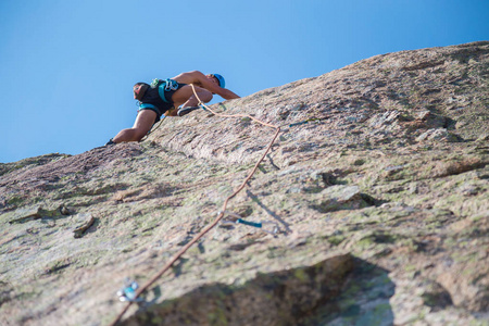 从下面拍摄的登山者爬上山墙在惊人的晴天