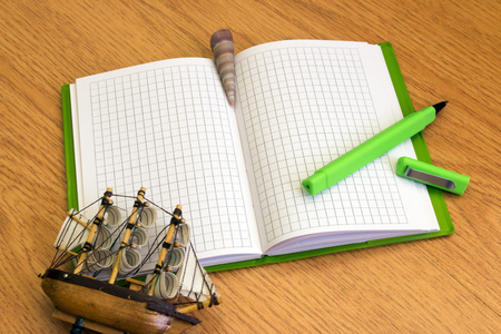 绿色的钢笔和贝壳在桌上的笔记本