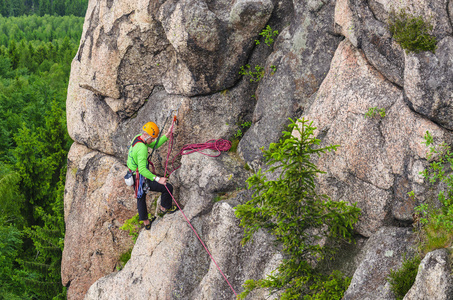 困难的垂直下降男子爬上岩石照片