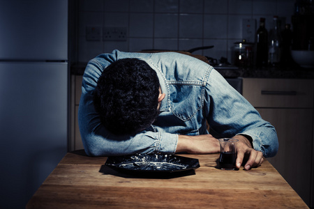 晚餐后喝酒的悲伤和孤独的男人一个孤独的年轻人独自在酒吧喝酒.