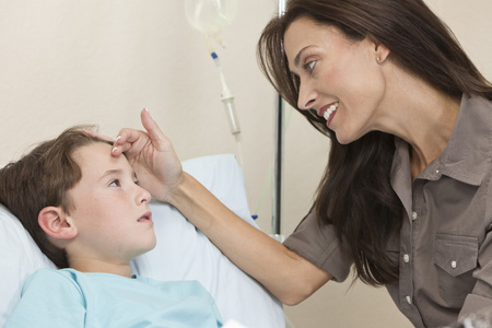 年轻的男孩儿童患者在医院的床上与母亲