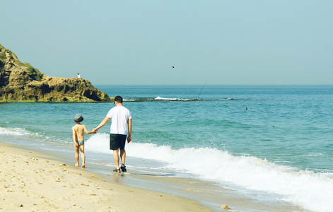 父亲和儿子在一起在沙滩上散步