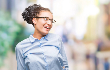 年轻的编织头发非洲裔美国女商人戴眼镜在孤立的背景看着一边面带微笑, 自然的表情。笑自信