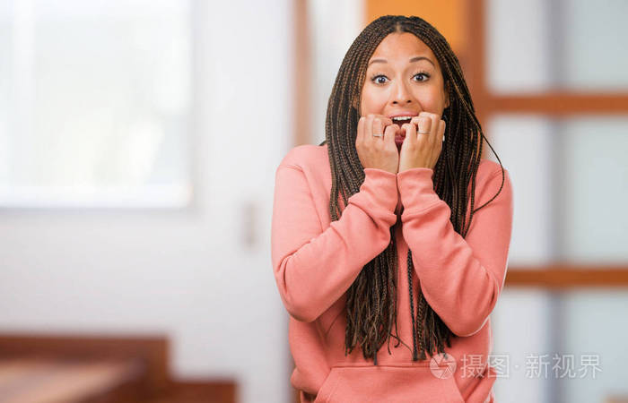 一个年轻的黑人妇女的肖像戴辫子咬钉子紧张非常焦虑和恐惧的未来感到