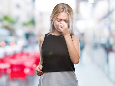 年轻的金发女人在孤立的背景下疲惫的摩擦鼻子和眼睛感到疲劳和头痛。压力和挫折概念