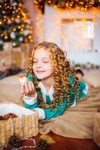 可爱的小女孩, 金色的卷发在家里附近的圣诞树与礼品和花环和装饰壁炉