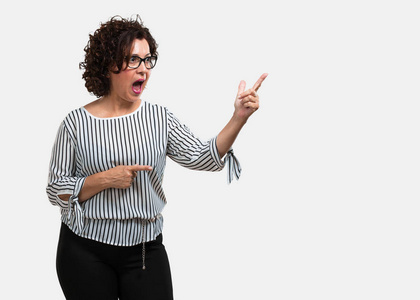 中年妇女自然中年妇女指着侧面, 微笑着惊讶地呈现的东西, 自然和休闲