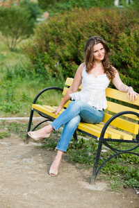 美丽的女人坐在公园的长凳上，