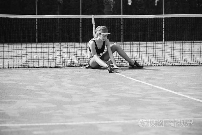 女人坐在放松上帽网球场