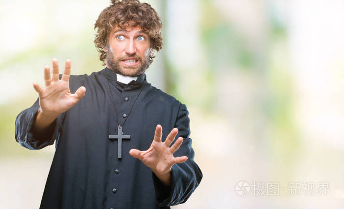 摄图新视界>照片>英俊的拉美裔天主教神父在孤立的背景下害怕和恐惧的