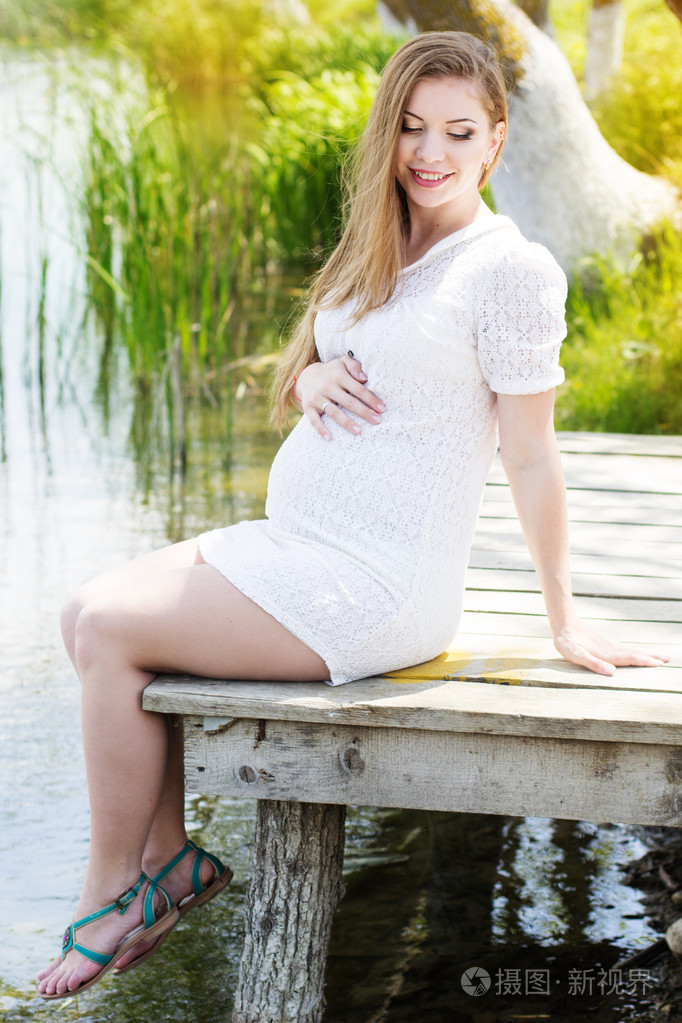 怀孕的女人坐在靠近河的桥