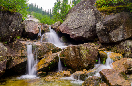 快速的瀑布巨大的石头环绕着河上的瀑布.快速的白色溪流穿过石头.