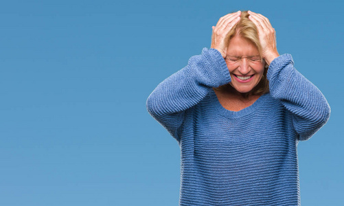 中年金发女子穿着冬季毛衣在孤立的背景下患头痛绝望和紧张, 因为疼痛和偏头痛。手在头上