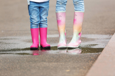 母亲和女儿穿着橡胶靴在街上, 特写