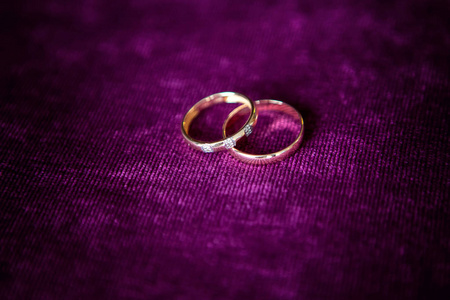 两个金结婚戒指查出的紫色, 结婚戒指背景概念