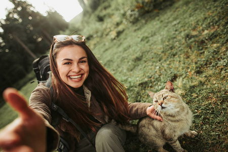 愉快的女孩在森林旅行期间做自拍与可爱的猫