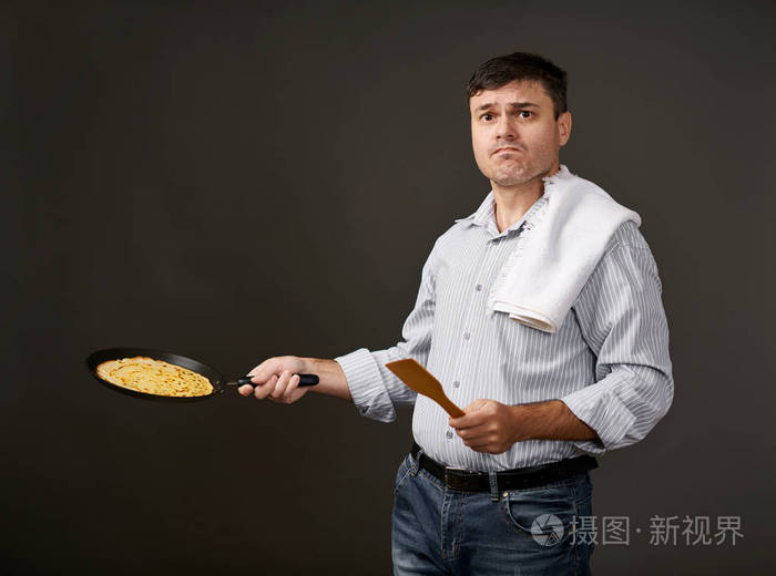 男子摆在平底锅煎饼, 白色衬衫和裤子, 灰色背景, 惊讶的情绪