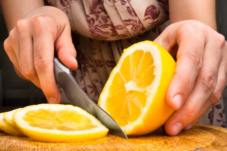 用刀在切菜板上切片柠檬照片