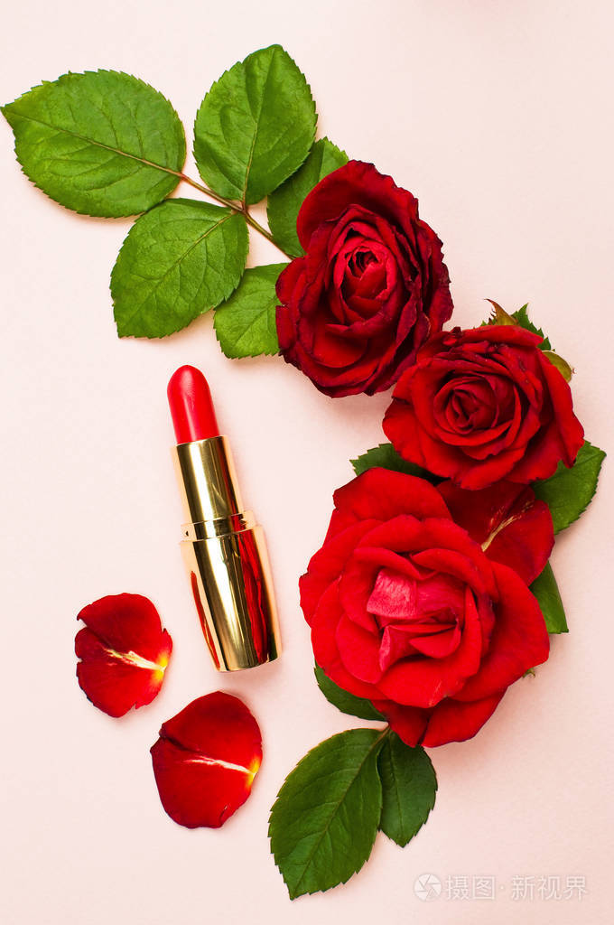 红色的口红与红色玫瑰在粉红色背景与复制空间化妆配件顶部视图平躺