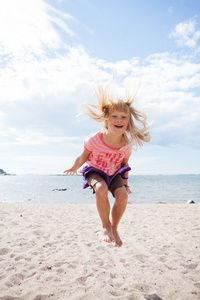 在海滩上跳跃的年轻女孩
