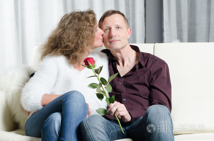 夫妇与玫瑰亲吻在沙发上