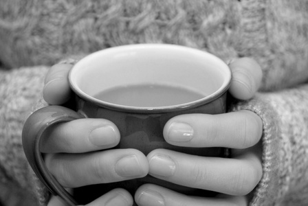 两只手保持温暖，手握一杯热咖啡或茶