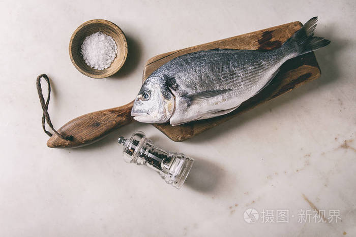 在白色大理石背景下 用冰 盐和胡椒制成的木制切割板上的未加工的生吃的海鲷或金鱼鱼 平躺 复制空间 烹饪理念照片 正版商用图片0bjndx 摄图新视界