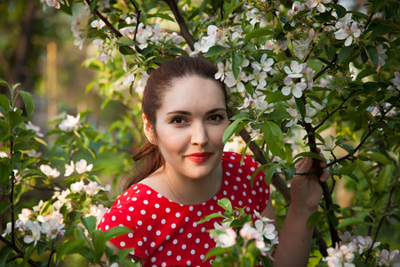 一个漂亮的女孩，在郁郁葱葱的苹果园的肖像