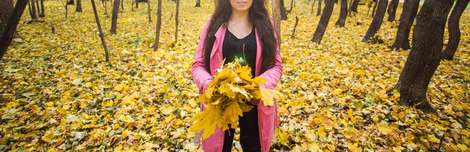 季节, 乐趣和喜悦概念年轻美丽的妇女在粉红色夹克捧着秋叶花束