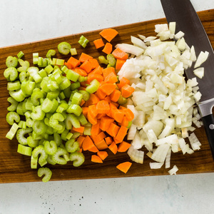 在木制砧板上切碎的蔬菜和厨师的刀。餐厅或家常菜的基本切割