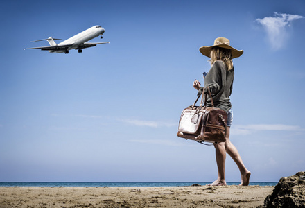 与老式皮革旅行袋在海滩上的女人