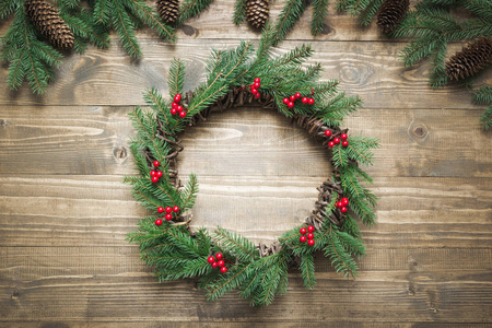由云杉的树枝和冬青浆果制成的圣诞花环在木板上。平躺。顶部视图。复制空间