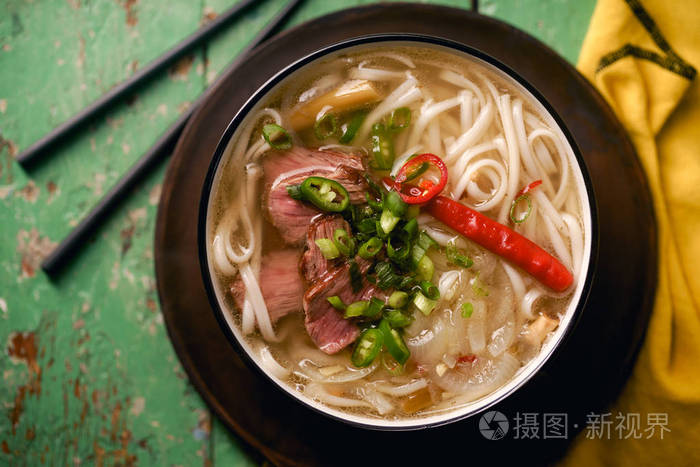 传统越南河汤配牛肉和新鲜香菜在质朴的木桌上