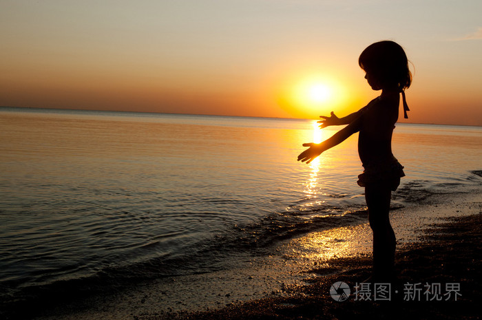 日落海滩上小女孩开心儿童剪影
