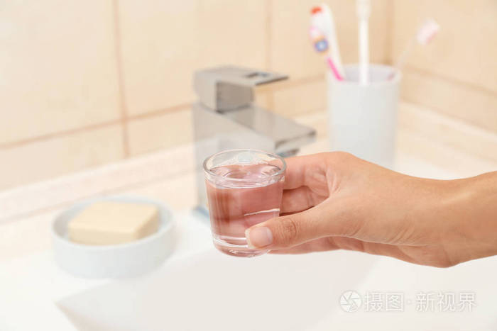 洗手间用漱口水和口腔护理的妇女手持玻璃