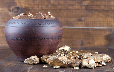 金币在陶瓷锅及其枚金币，木制的背景上