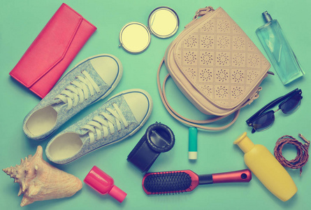 顶部视图的少女春季夏季配件 运动鞋, 化妆品, 美容和卫生产品, 袋子, 太阳镜在蓝色柔和的背景。去旅行