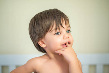 可爱的男婴幼儿在婴儿床手指在嘴