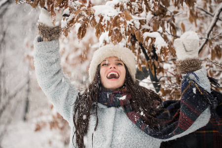 站在白雪覆盖的公园里的快乐年轻美丽的女人的肖像