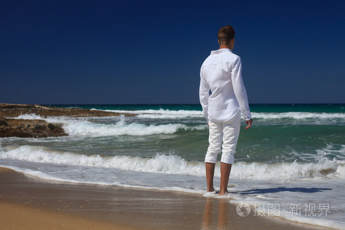 一个年轻人背对着海滩站着