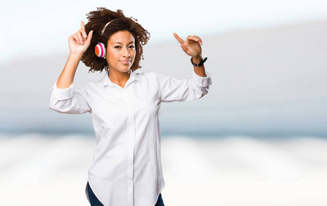 年轻的黑人妇女使用耳机和舞蹈在模糊的背景