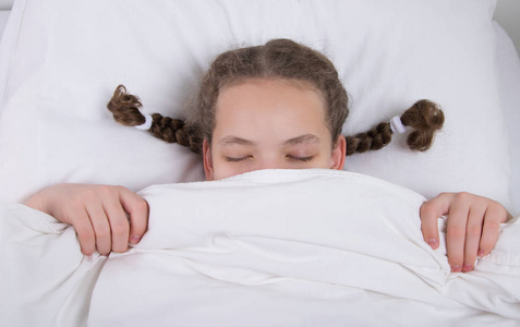 躺在毯子的女孩在枕头上的两个辫子