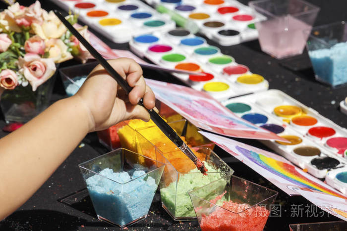 孩子的手拿着画笔在一个阳光明媚的日子外面的创意车间里画画.特写