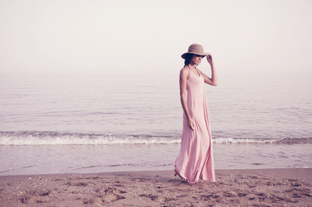 热带海滩上长粉红色裙子的美丽女人