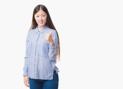 年轻的中国妇女在孤立的背景做愉快的拇指手势与手。批准表达式看着相机显示成功