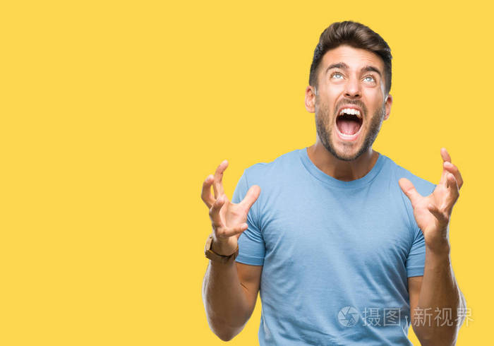 年轻英俊的男人在孤立的背景下疯狂和疯狂的呼喊和激烈的表达和手臂