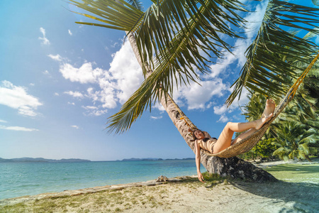 夏日假期的概念, 穿着泳装的女人在巴拉望岛的热带海滩上的吊床上放松, 菲律宾