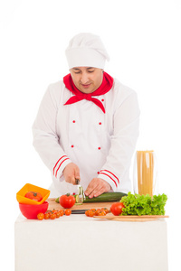 快乐的厨师烹饪与身穿红色和白色的新鲜蔬菜